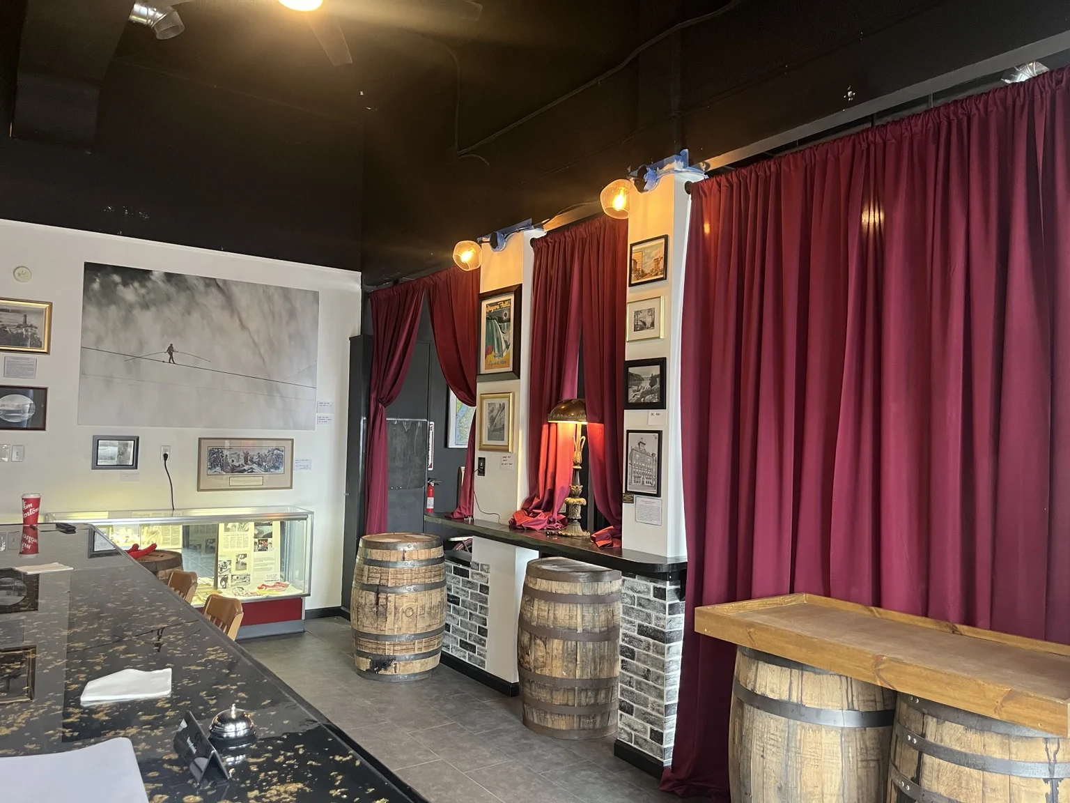 Barrel tables and exhibits framed by burgundy curtains