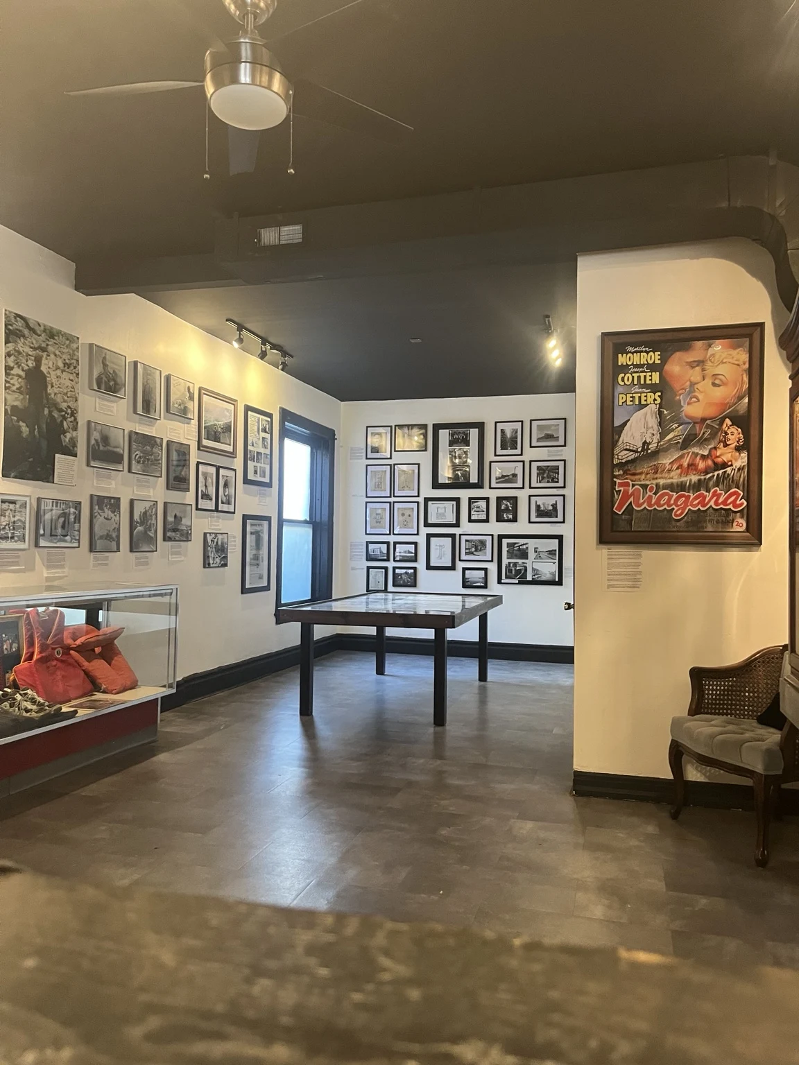 Upstairs museum gallery with vintage Niagara Falls photographs, artifact displays, and a Niagara movie poster